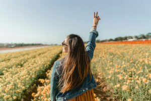 A woman enjoying a sunny day in a vivid yellow flower field in Carlsbad, CA.